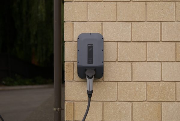 Laadvoorziening gemonteerd aan een gevelmuur, met laadkabel aangesloten op een elektrische auto