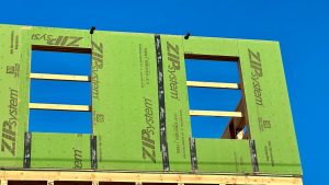 Zelf bouwen woning met groene bouwpanelen en open raamconstructies in houten gevel