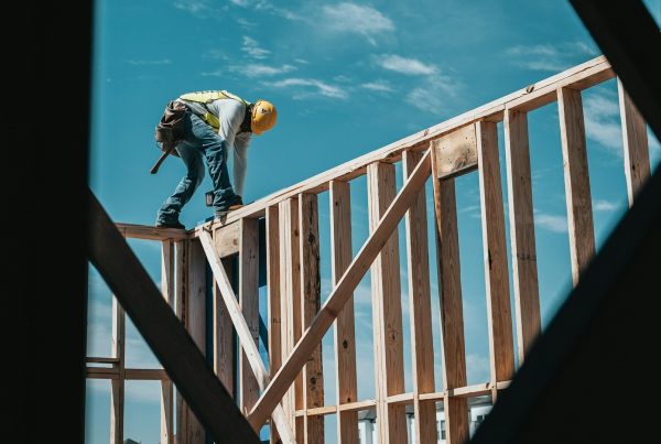Zelf bouwen woning met bouwvakker die houten frameconstructie van een huis monteert op bouwplaats
