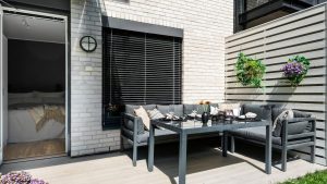 Kleine patio met hoekbank en wanddecoratie als inspiratie voor kleine tuin inrichten met zitruimte