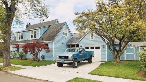 Woning met stijlvolle oprit, nette voortuin en klassieke garage aan de straatzijde.