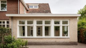 Aanbouw van een woning met nieuwe witte kozijnen en grote raampartijen